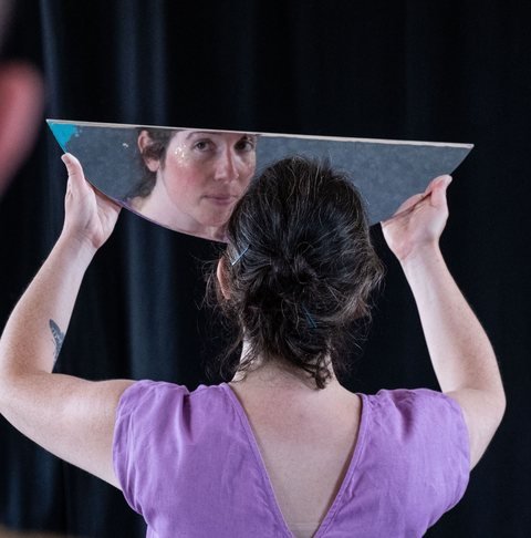 Mélody Blocquel, de dos, tient un miroir où se reflète son visage