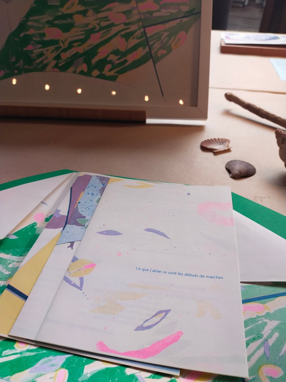 Pages de Peuplé·e·s étalées sur une table, près d’un miroir lumineux