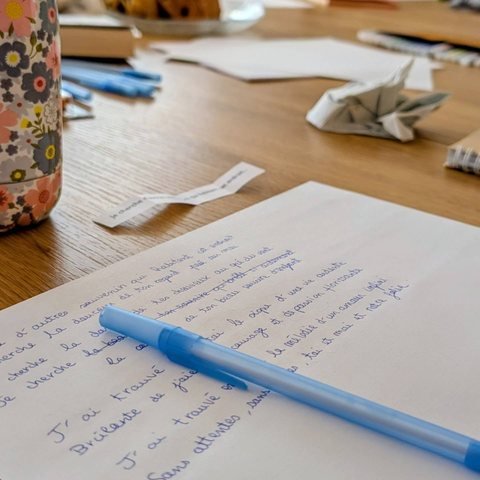 Texte manuscrit et stylo bleu sur une table d’atelier d’écriture