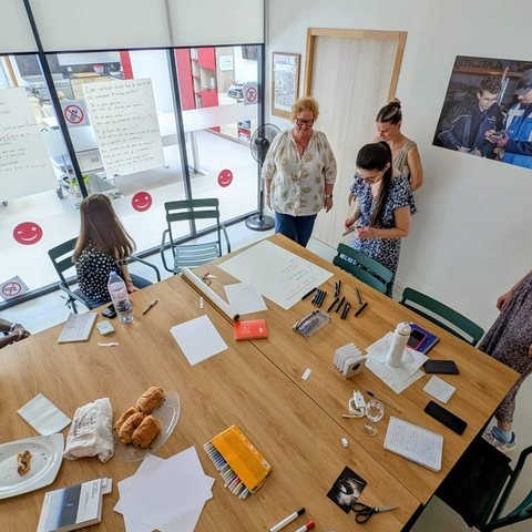Atelier autour d’une grande table couverte de papiers et de feutres
